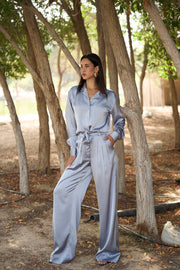 Woman in a light blue outfit standing among trees